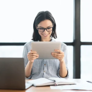 young-girl-holding-tablet-and-using-laptop-at-offi-2022-12-16-08-47-48-utc1.webp